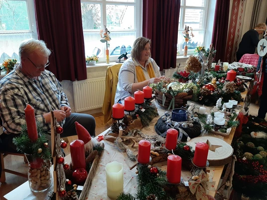 Weihnachtsmarkt Tange.jpg Menschen verkaufen Adventsgestecke mit roten Kerzen und Tannenzweigen auf einem Weihnachtstisch.People selling Advent arrangements with red candles and fir branches on a Christmas table.Folk sælger adventsarrangementer med røde lys og grangrene på et julebord.Mensen verkopen adventsarrangementen met rode kaarsen en dennentakken op een kersttafel.