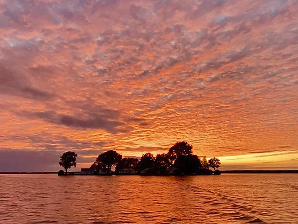 Sonnenuntergang Wellen des Meeres spiegeln die leuchtenden Rot- und Orangetöne eines lebhaften Sonnenuntergangs wider.