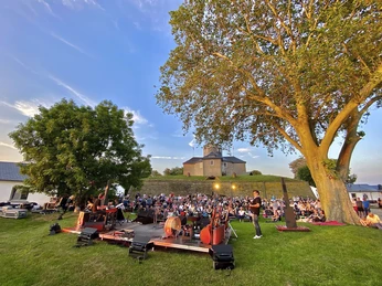 Veranstaltung Wilhelmstein Open-Air-Konzert auf einer grünen Wiese vor einer historischen Festung bei Sonnenuntergang.Open-air concert on a green meadow in front of a historic fortress at sunset.Open-air koncert på en grøn eng foran en historisk fæstning ved solnedgang.Openluchtconcert op een groene weide voor een historisch fort bij zonsondergang.