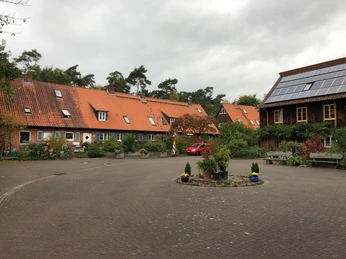 A communal residential courtyard with red tiled roofs, surrounded by trees and green spaces.