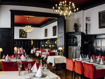 Ratskeller-Wiedenbrueck-290619-Karti-Fotografie-326.jpg Elegantes Restaurant mit roten Polstern, weißen Tischdecken und Kronleuchtern in stilvollem Ambiente.