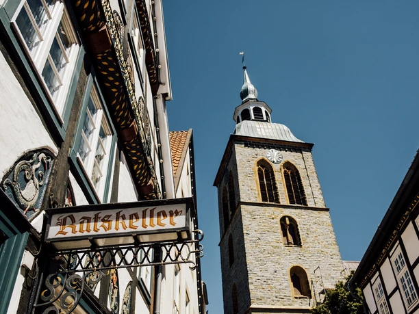 Fachwerkhäuser und der Kirchturm von St. Dionys bei sonnigem Himmel in Lemgo.