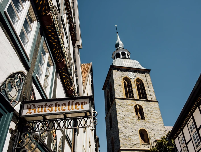 Fachwerkhäuser und der Kirchturm von St. Dionys bei sonnigem Himmel in Lemgo.