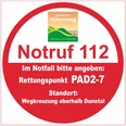 Runder Rettungspunkt-Aufkleber im Paderborner Höhenweg mit Notruf 112 und PAD2-7 für Notfälle.