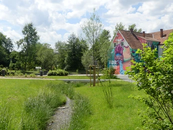 Graffiti eines großen roten Herzens auf einem bunten Haus in einem grünen städtischen Parkbereich.