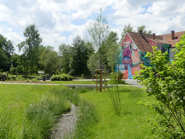 Graffiti eines großen roten Herzens auf einem bunten Haus in einem grünen städtischen Parkbereich.