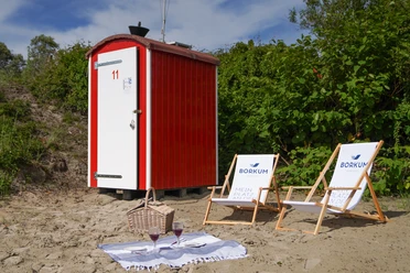 2021_06 - BA NBG FKK Budjes-2128.jpg Rote FKK-Bude, zwei weiße Liegestühle und Picknickplatz mit Decke, Korb und Weingläsern auf dem Boden
