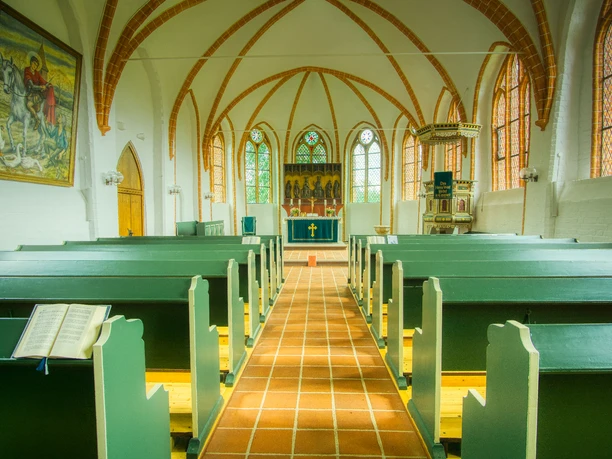 St. Martins-Kirche in Soderstorf Innenraum Blick durch den Kircheninnenraum mit grünen Bänken und Gewölbedecke zum Altar.