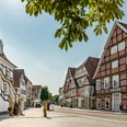 Historische Fachwerkhäuser säumen eine sonnige Straße in einer charmanten deutschen Altstadt.