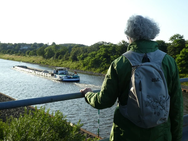 Schleusenkanal Etelsen Eine Person mit grünem Rucksack blickt auf ein Binnenschiff, das den Schleusenkanal Etelsen befährt.