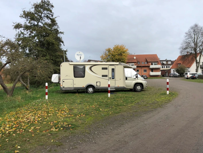 Wohnmobil auf grünem Stellplatz in Steyerberg, umgeben von Herbstlaub und nahe gelegenen Häusern.