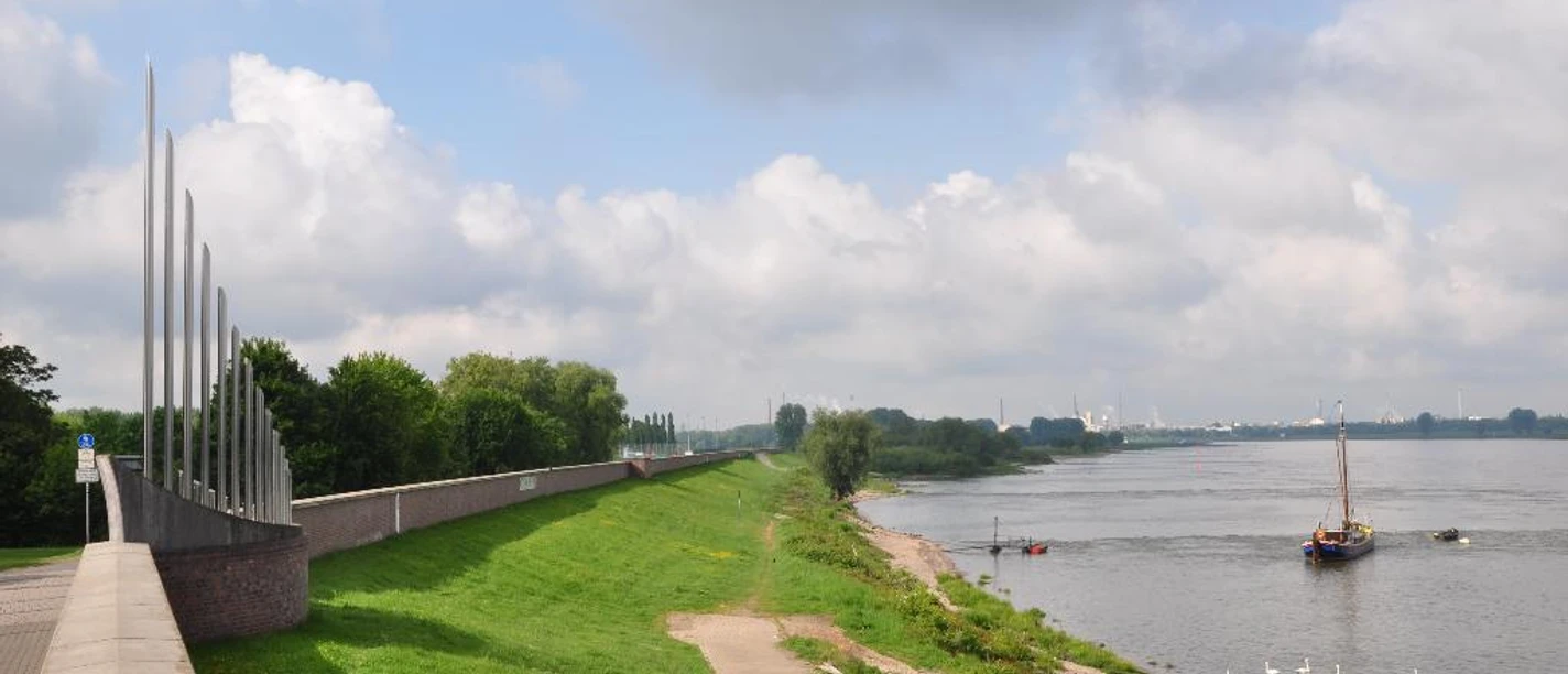 Deich Monheim am Rhein Grüner Deichabschnitt entlang des Rheins in Monheim, gesäumt von Wegen und ankernden Booten einstellen.