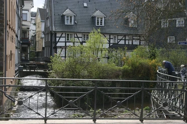 Velbert Langenberg Historische Fachwerkhäuser mit Graudächern säumen einen plätschernden Bach in Velbert Langenberg.
