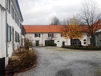 Haus Morp in Erkrath Historischer Gebäudekomplex mit weißer Fassade, roten Ziegeldächern und gepflastertem Vorplatz.