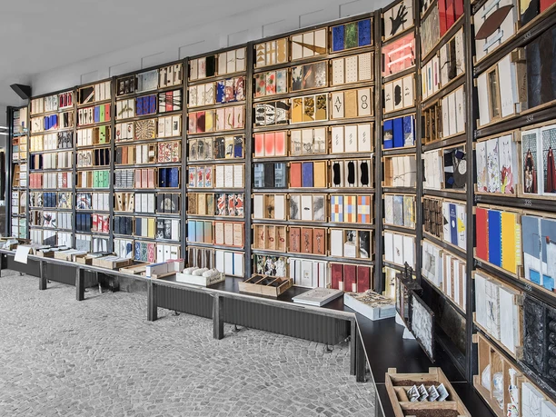 Grundsteinkiste in Velbert-Langenberg Vielzahl von Büchern in farbenfrohen Umschlägen geordnet in einem Regal auf grauem Boden.