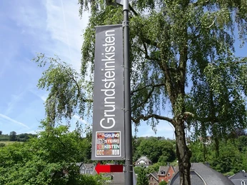 Straßenschild der Grundsteinkisten in Velbert-Langenberg Ein hohes Schild im Ortsteil Langenberg in Velbert wirbt für die Grundsteinkisten mit einem Hinweis.