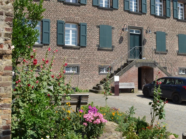 Blick auf Haus Bürgel im Sommer Der historische Gebäudekomplex von Haus Bürgel präsentiert sich mit bunter Sommerblumenbepflanzung.