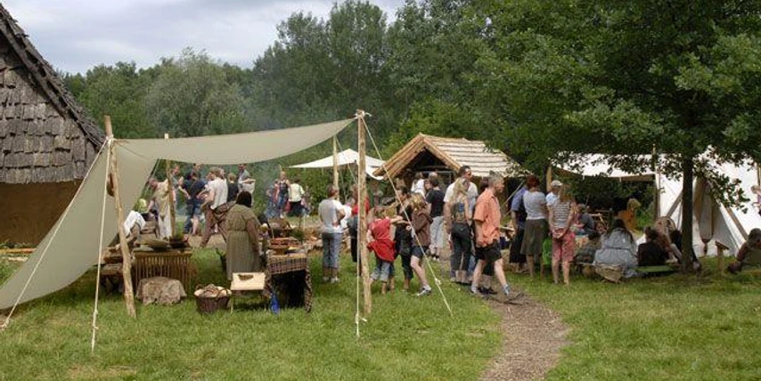 Eisenzeitlicher Handwerkermarkt Besucher erkunden handgefertigte Waren und traditionelle Techniken auf einem historischen Handwerkermarkt.