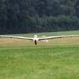 LSG Erbslöh Ein Segelflugzeug im Landeanflug auf eine grüner Landingstrip mit Waldrand im Hintergrund.