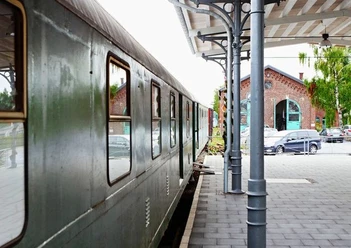 Bahnsteig am Lokschuppen (Erkrath-Hochdahl) Grüner Zug parkt am Bahnsteig neben dem historischen Lokschuppen mit markantem Rundbogenfenster.
