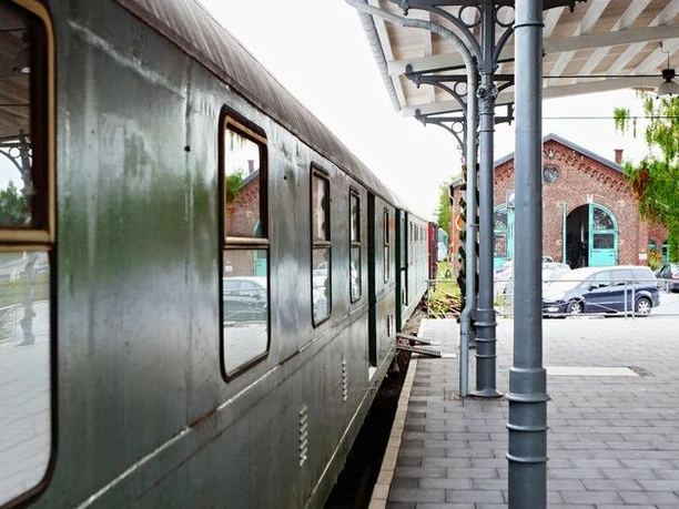 Bahnsteig am Lokschuppen (Erkrath-Hochdahl) Grüner Zug parkt am Bahnsteig neben dem historischen Lokschuppen mit markantem Rundbogenfenster.