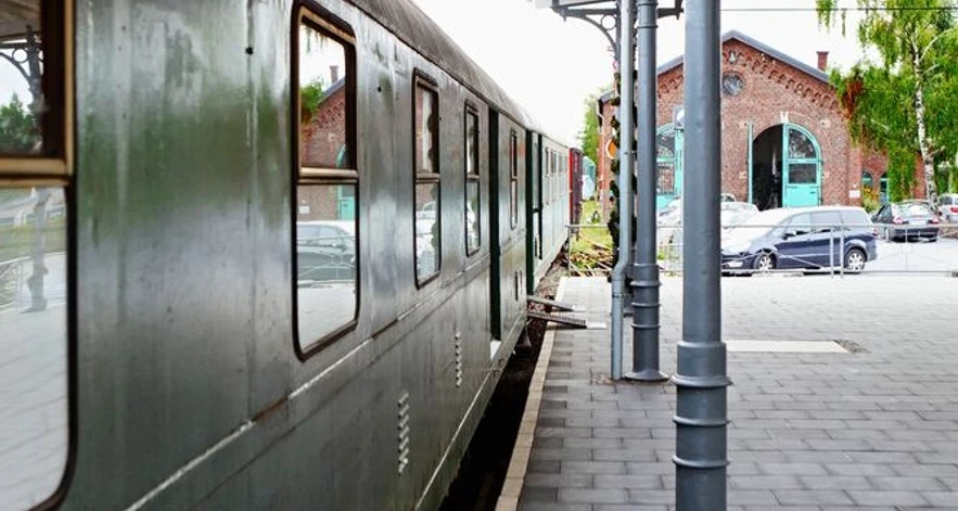 Bahnsteig am Lokschuppen (Erkrath-Hochdahl) Grüner Zug parkt am Bahnsteig neben dem historischen Lokschuppen mit markantem Rundbogenfenster.