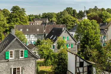 Aussicht auf Haan-Gruiten Historische Fachwerkhäuser neben grünen Baumkronen unter blauem Himmel in Haan-Gruiten.