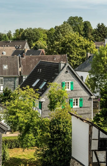 Aussicht auf Haan-Gruiten Historische Fachwerkhäuser neben grünen Baumkronen unter blauem Himmel in Haan-Gruiten.