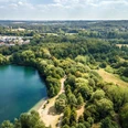 Blick auf den Grünen See bei Ratingen Luftaufnahme eines grünen Sees inmitten von dichtem Wald und angrenzenden Wohngebieten bei Tageslicht.