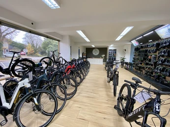 Bikefactory4.jpeg Ein moderner Fahrradladen mit vielen E-Bikes auf Holzboden. Helle LED-Beleuchtung rundet das Ambiente ab.