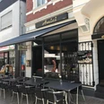 Amici - caffè e più (Bistro) Bistro Amici mit Außensitzplätzen, modernem Design und markanter Straßenansicht in städtischer Umgebung.