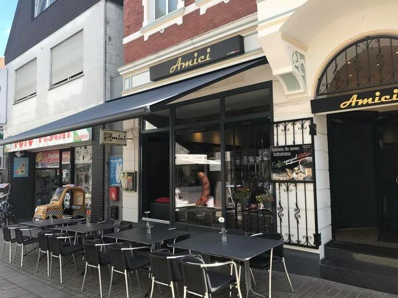 Amici - caffè e più (Bistro) Bistro Amici mit Außensitzplätzen, modernem Design und markanter Straßenansicht in städtischer Umgebung.