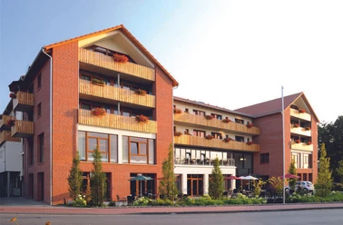 Landhotel Rotes Backsteingebäude mit mehreren Stockwerken, Balkonen und großen Fenstern in ruhiger Umgebung.