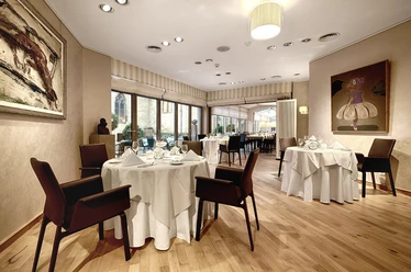 Reuter_2 Elegantes Restaurant mit gedeckten Tischen, modernen Kunstwerken und großen Fenstern mit Aussicht.