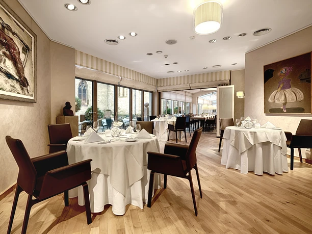 Reuter_2 Elegantes Restaurant mit gedeckten Tischen, modernen Kunstwerken und großen Fenstern mit Aussicht.