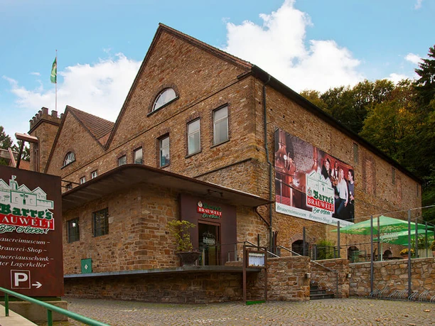 Barres Brauwelt Historisches Backsteingebäude von Barres Brauwelt, umgeben von grünen Bäumen und gepflastertem Weg.