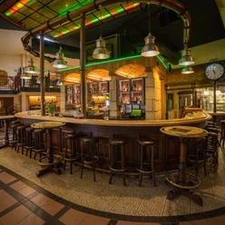 Brauhaus Espelkamp Große, rustikale Bar mit Holzhockern, umgeben von warmem Licht. Industrielle Lampen hängen über der Theke.
