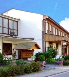Schöller Café - Konditorei Schöller Café mit moderner Fassade und blühenden Pflanzen in einem gepflegten Vorgarten.