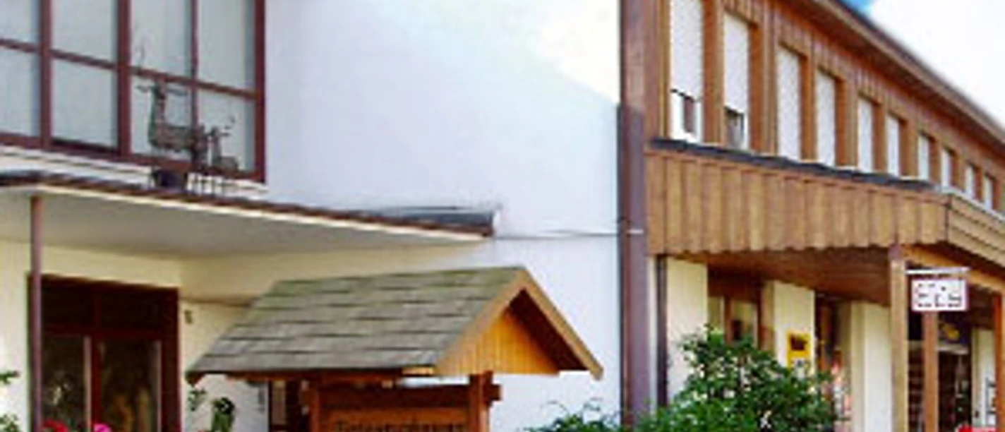 Schöller Café - Konditorei Schöller Café mit moderner Fassade und blühenden Pflanzen in einem gepflegten Vorgarten.