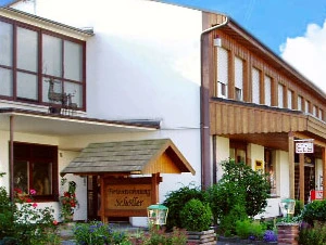 Schöller Café - Konditorei Schöller Café mit moderner Fassade und blühenden Pflanzen in einem gepflegten Vorgarten.