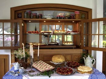Landhaus Röscher Ein Holzbuffet mit offenen Türen präsentiert ein üppiges Angebot an Kuchen und Torten auf mehreren Etagen.