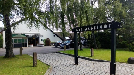 Steakhaus Gut Jägerhof in Erkrath Eingang zum Steakhaus Gut Jägerhof in Erkrath mit gepflastertem Weg, Bäumen und geparkten Autos.