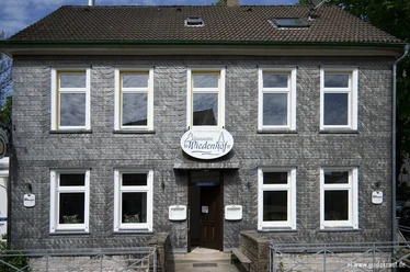 Frontansicht vom Palazzo Wiedenhof in Haan Zweistöckiges Gebäude mit grauer Schieferfassade und weißen Fensterrahmen in Haan.