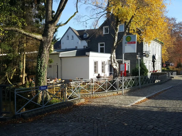 Bushaltestelle direkt am Palazzo Wiedenhof in Haan Bushaltestelle in Haan vor dem historischen Palazzo Wiedenhof, umgeben von herbstlichen Bäumen.