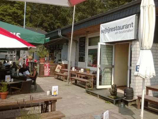 Se(h)-Restaurant Unterbacher See Das Se(h)-Restaurant am Unterbacher See bietet Sitzgelegenheiten und eine Außenansicht des Gebäudes.