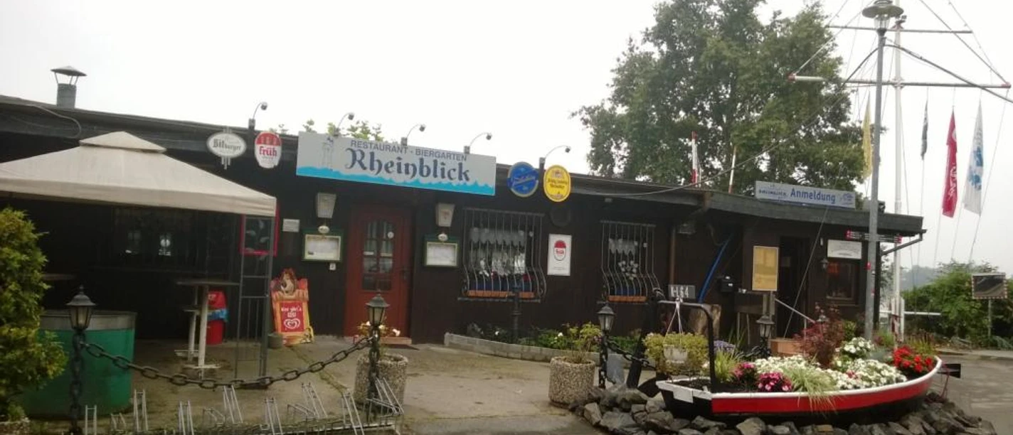 Ein uriges Restaurant mit Holzfassade, maritimem Dekor und liebevoll gepflegten Pflanzenarrangements.