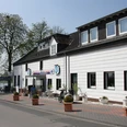 Baumberger Rheinterrassen in Monheim am Rhein Restaurant mit weißer Fassade, Blumenkübeln und angrenzender Terrasse mit Aussicht auf den Rhein.