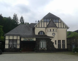 Historisches Gebäude mit Fachwerkfassade und Turm, genannt Alter Bahnhof. Uhr und Eingang erkennbar.
