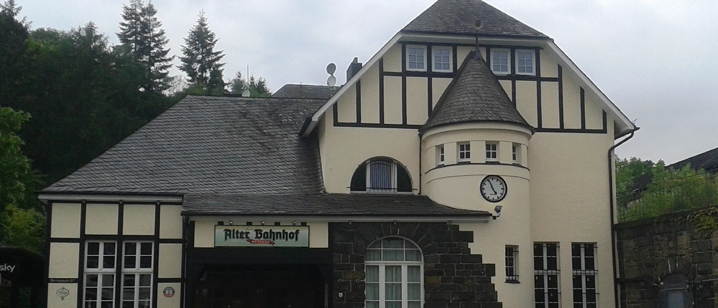 Historisches Gebäude mit Fachwerkfassade und Turm, genannt Alter Bahnhof. Uhr und Eingang erkennbar.