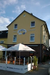 Ein gelbes Gebäude mit der Aufschrift "Knappmann Hotel Restaurant" und einem sonnigen Biergarten.